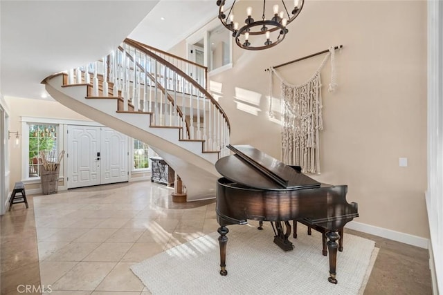 foyer entrance with stairway, a high ceiling, baseboards, and an inviting chandelier