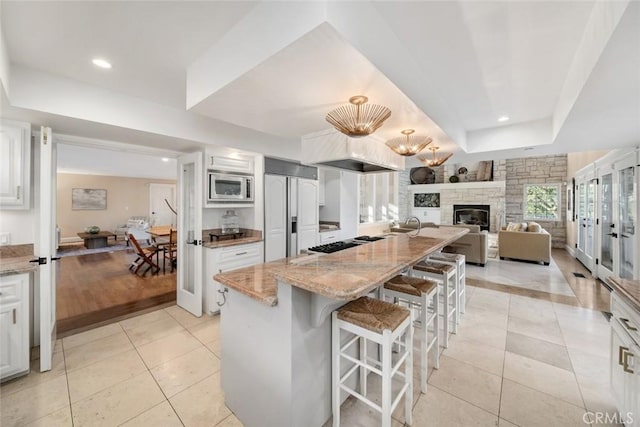 kitchen featuring light stone countertops, light tile patterned floors, a tray ceiling, and built in appliances