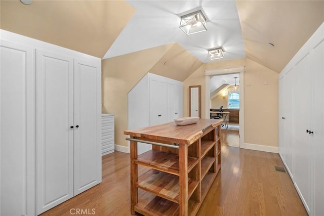 bonus room with light wood finished floors, baseboards, and vaulted ceiling