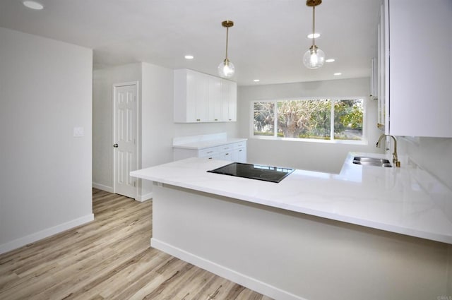 kitchen featuring hanging light fixtures, sink, black electric stovetop, and kitchen peninsula