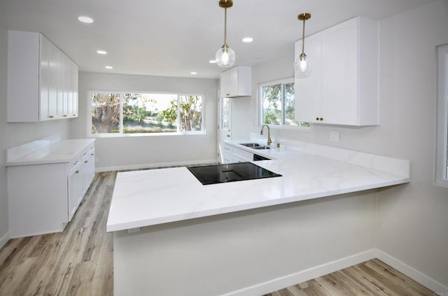 kitchen featuring sink, hanging light fixtures, black electric stovetop, white cabinets, and kitchen peninsula