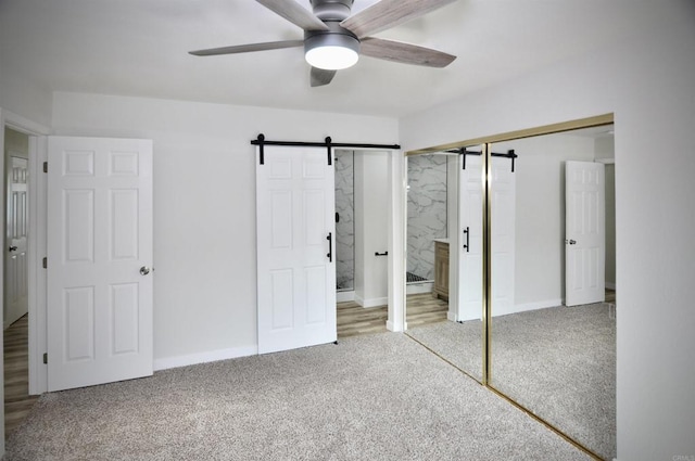 unfurnished bedroom with light carpet, connected bathroom, a closet, and a barn door