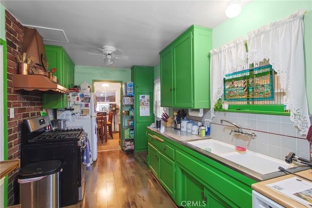 kitchen with dark wood-type flooring, stainless steel gas range, ceiling fan, backsplash, and green cabinetry