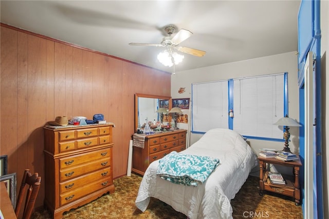 bedroom with ceiling fan and wooden walls