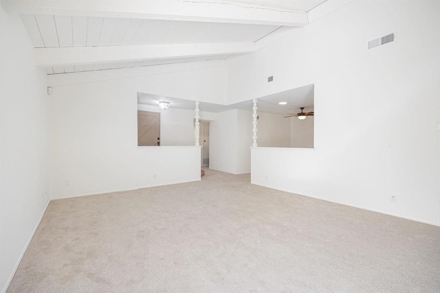 empty room featuring light colored carpet and lofted ceiling with beams