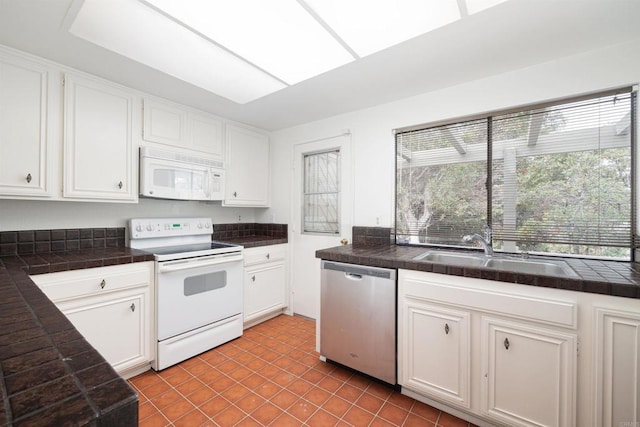 kitchen featuring sink, white cabinets, white appliances, and a skylight