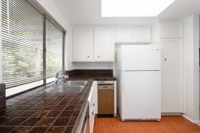 kitchen with sink, light tile patterned floors, white refrigerator, dishwashing machine, and white cabinets