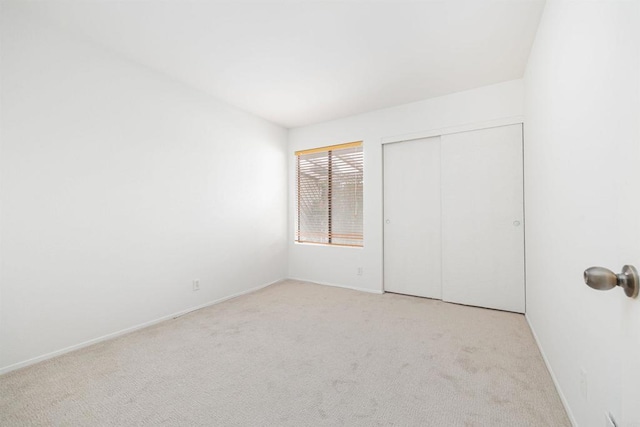 unfurnished bedroom with light colored carpet and a closet