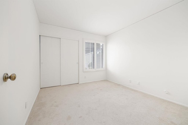 unfurnished bedroom featuring light colored carpet and a closet