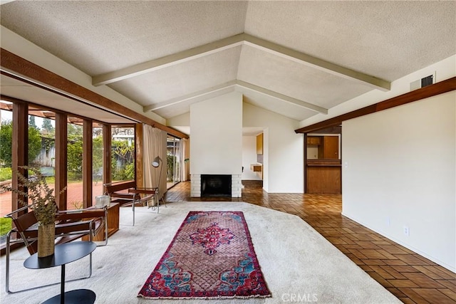 living room with a fireplace, a textured ceiling, and vaulted ceiling with beams