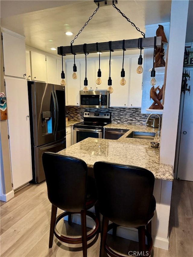 kitchen with white cabinetry, appliances with stainless steel finishes, sink, and kitchen peninsula