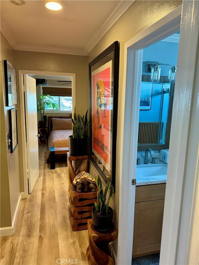 corridor with sink, light hardwood / wood-style flooring, and ornamental molding