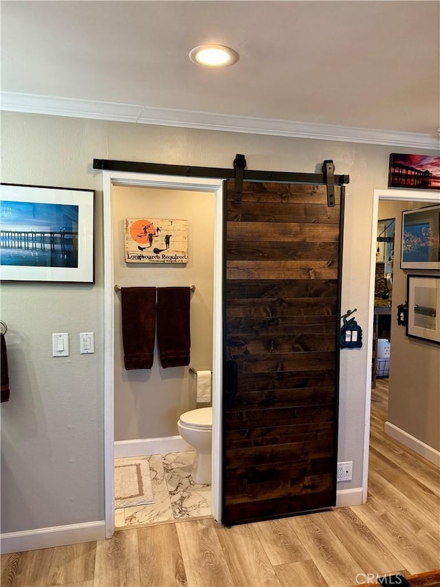 bathroom featuring crown molding, hardwood / wood-style floors, and toilet