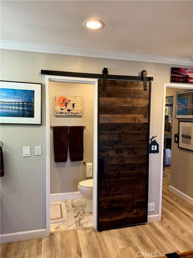 bathroom featuring baseboards, wood finished floors, and crown molding