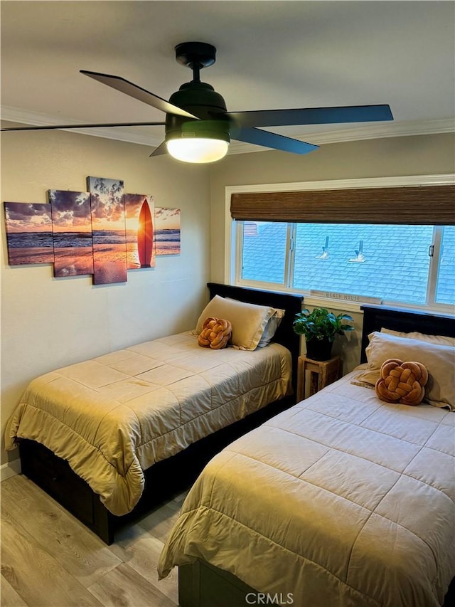 bedroom with multiple windows, wood finished floors, a ceiling fan, and ornamental molding