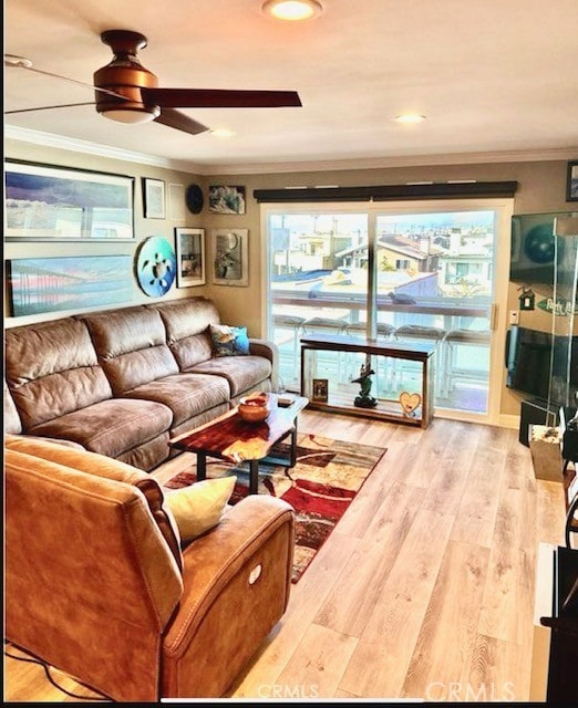 living area with ornamental molding, a ceiling fan, and wood finished floors