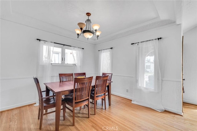 dining area featuring a chandelier, a tray ceiling, light wood-type flooring, and baseboards