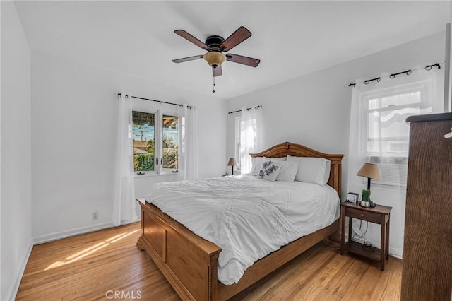 bedroom with light wood-style floors, ceiling fan, and baseboards