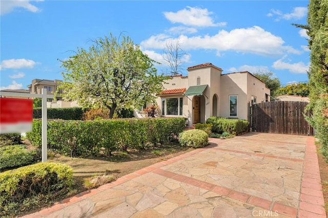 mediterranean / spanish house with a tiled roof, fence, and stucco siding