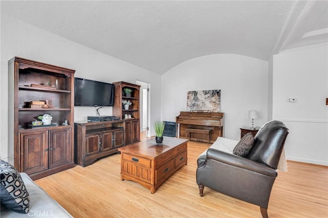 living room with vaulted ceiling, light wood finished floors, and baseboards