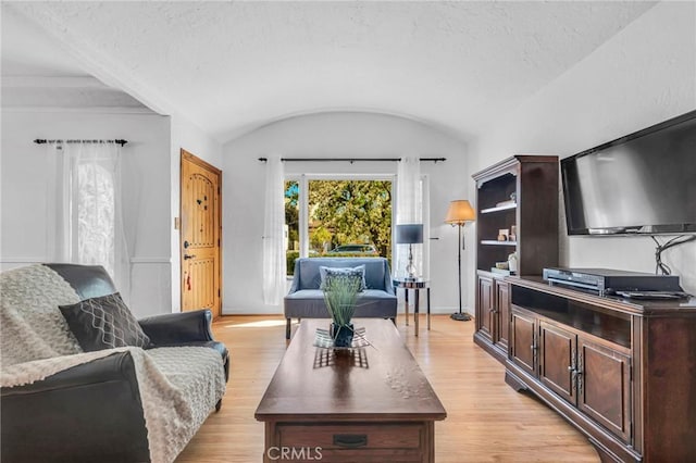 living room with baseboards, vaulted ceiling, and light wood finished floors