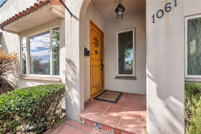 view of exterior entry featuring a tiled roof and stucco siding