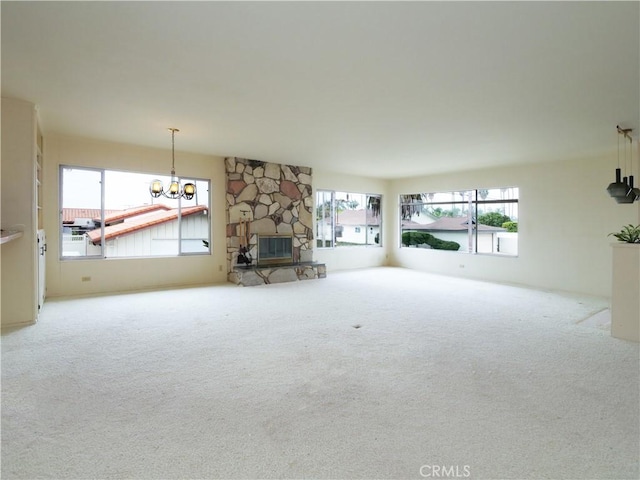 unfurnished living room featuring carpet flooring, a notable chandelier, and a fireplace