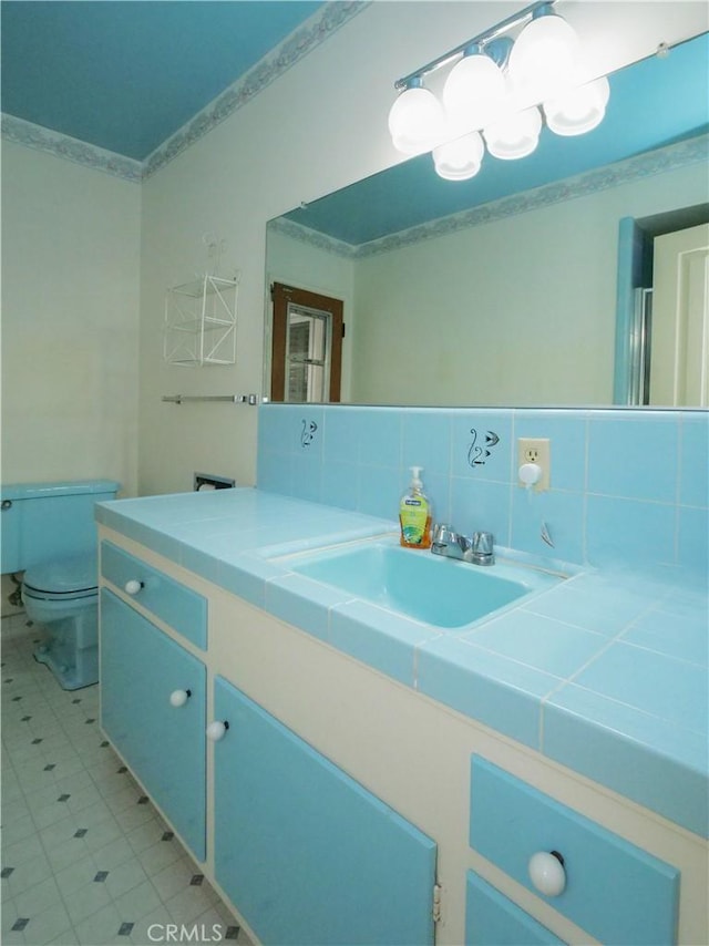 bathroom featuring crown molding, vanity, toilet, and backsplash