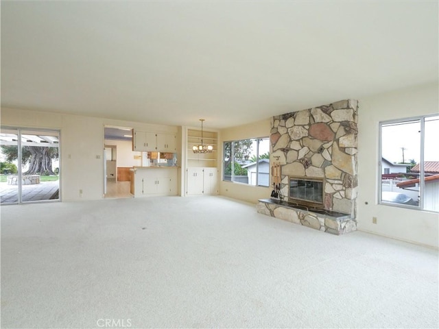 unfurnished living room with a fireplace, a chandelier, and carpet