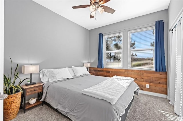 carpeted bedroom with ceiling fan and wooden walls