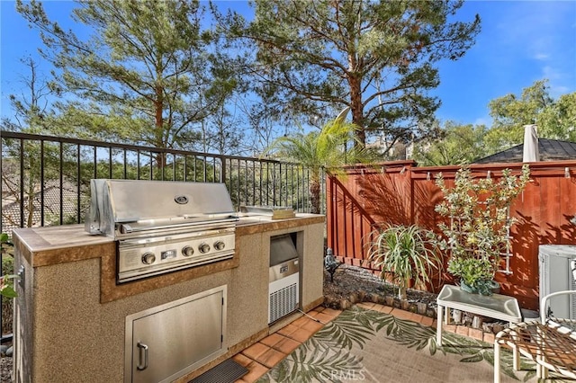 view of patio featuring a grill, central air condition unit, and exterior kitchen