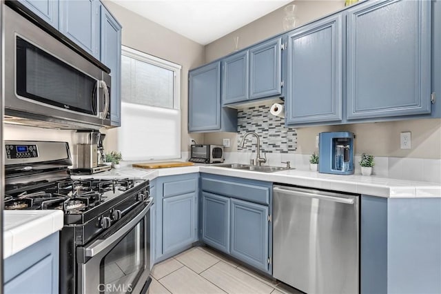 kitchen with sink, stainless steel appliances, and blue cabinetry