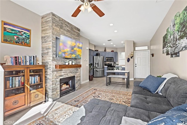 tiled living room featuring ceiling fan and a stone fireplace