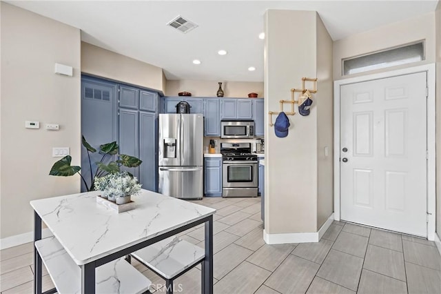 kitchen with light stone counters, stainless steel appliances, and blue cabinetry