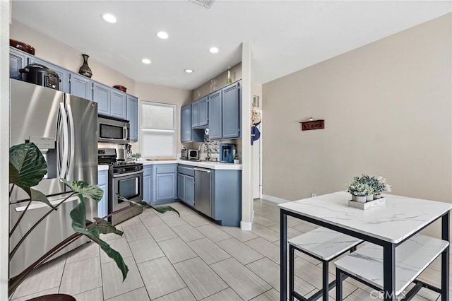 kitchen featuring tasteful backsplash, appliances with stainless steel finishes, and blue cabinets