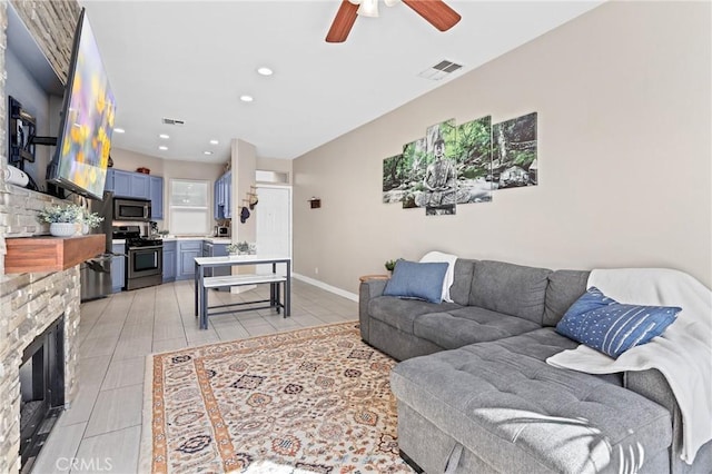 tiled living room featuring ceiling fan and a stone fireplace