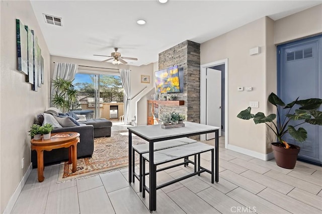 living room with ceiling fan and a stone fireplace