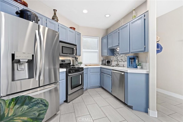 kitchen featuring sink, backsplash, stainless steel appliances, and blue cabinets