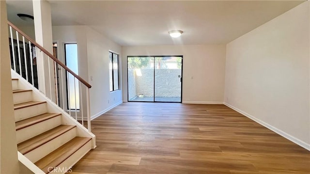 unfurnished room featuring stairway, baseboards, and wood finished floors