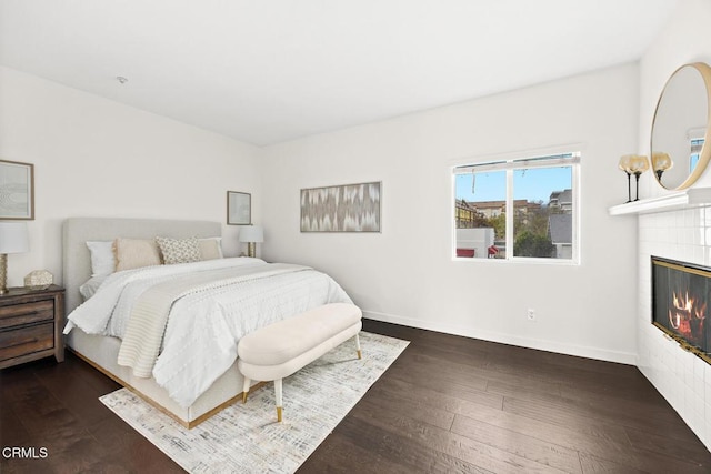 bedroom featuring a tile fireplace and dark hardwood / wood-style floors