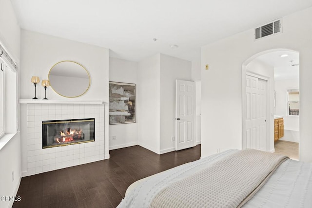 bedroom featuring a tiled fireplace and dark hardwood / wood-style floors