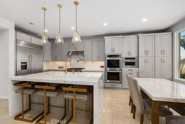 28622 Point Loma, Laguna Niguel, CA 92677 - kitchen with appliances with stainless steel finishes, under cabinet range hood, backsplash, light stone counters, and recessed lighting