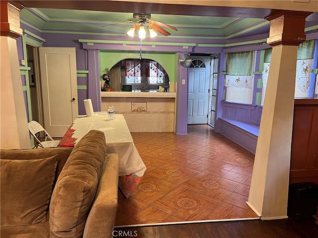 living room with ornate columns, crown molding, and ceiling fan