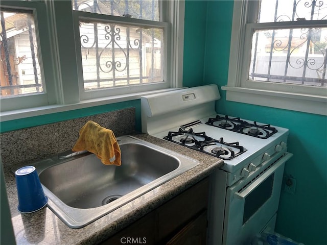 kitchen with sink, white gas range oven, and a healthy amount of sunlight