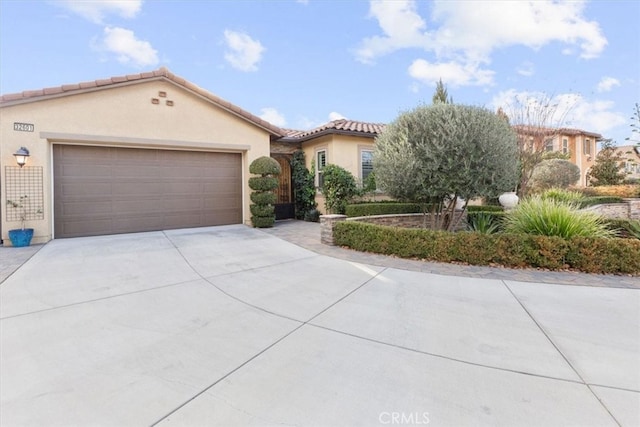 mediterranean / spanish-style house featuring a garage, a tile roof, driveway, and stucco siding