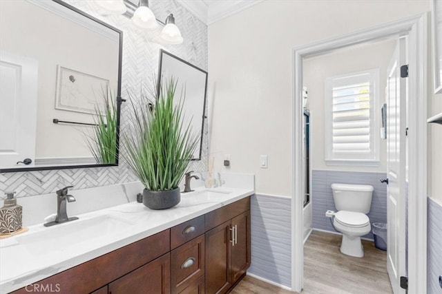 full bathroom featuring toilet, double vanity, tile walls, and a sink