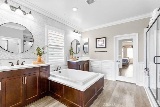 ensuite bathroom featuring a wainscoted wall, visible vents, a sink, and ornamental molding