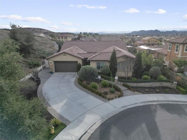 mediterranean / spanish-style home featuring stucco siding, an attached garage, a residential view, driveway, and a tiled roof