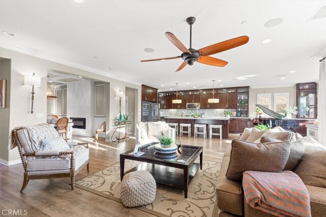 living room featuring ornamental molding, light wood-type flooring, visible vents, and a fireplace