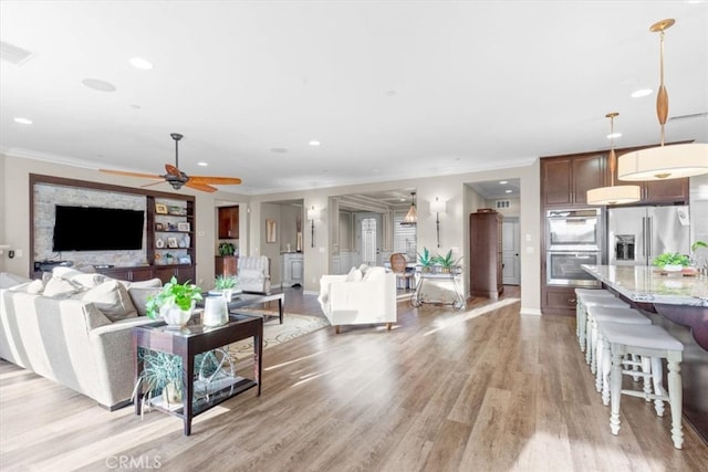 living area with light wood-style flooring, recessed lighting, a ceiling fan, baseboards, and crown molding